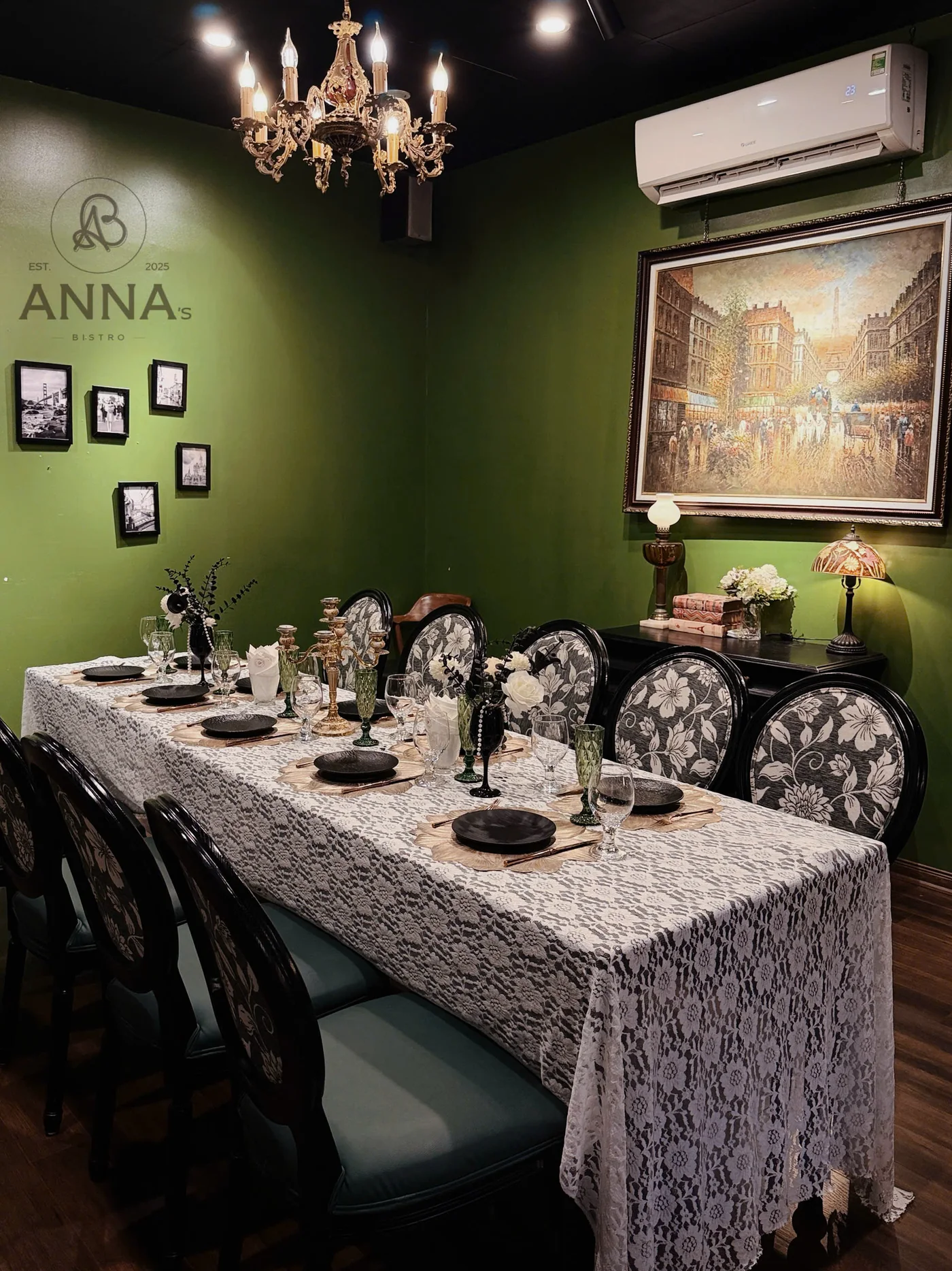 Không gian phòng ăn với tường xanh, đèn chùm và bàn dài tại Anna's Bistro