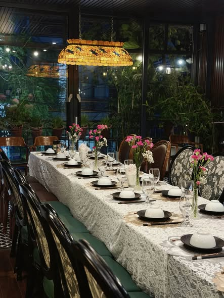 Bàn dài phủ ren dưới đèn kính màu trong không gian riêng của Anna's Bistro